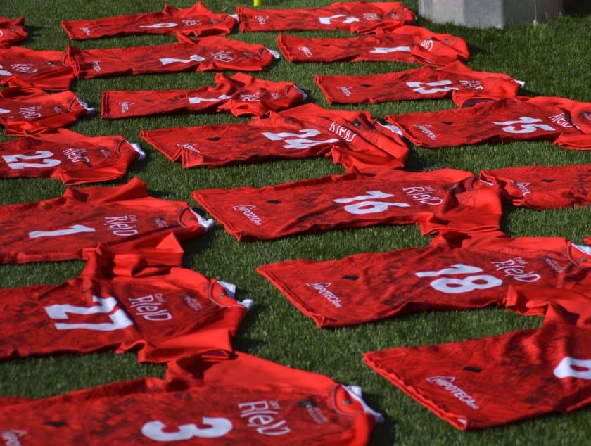 Camisetas rojas de Vallecas Rugby Unión preparadas sobre el césped del campo